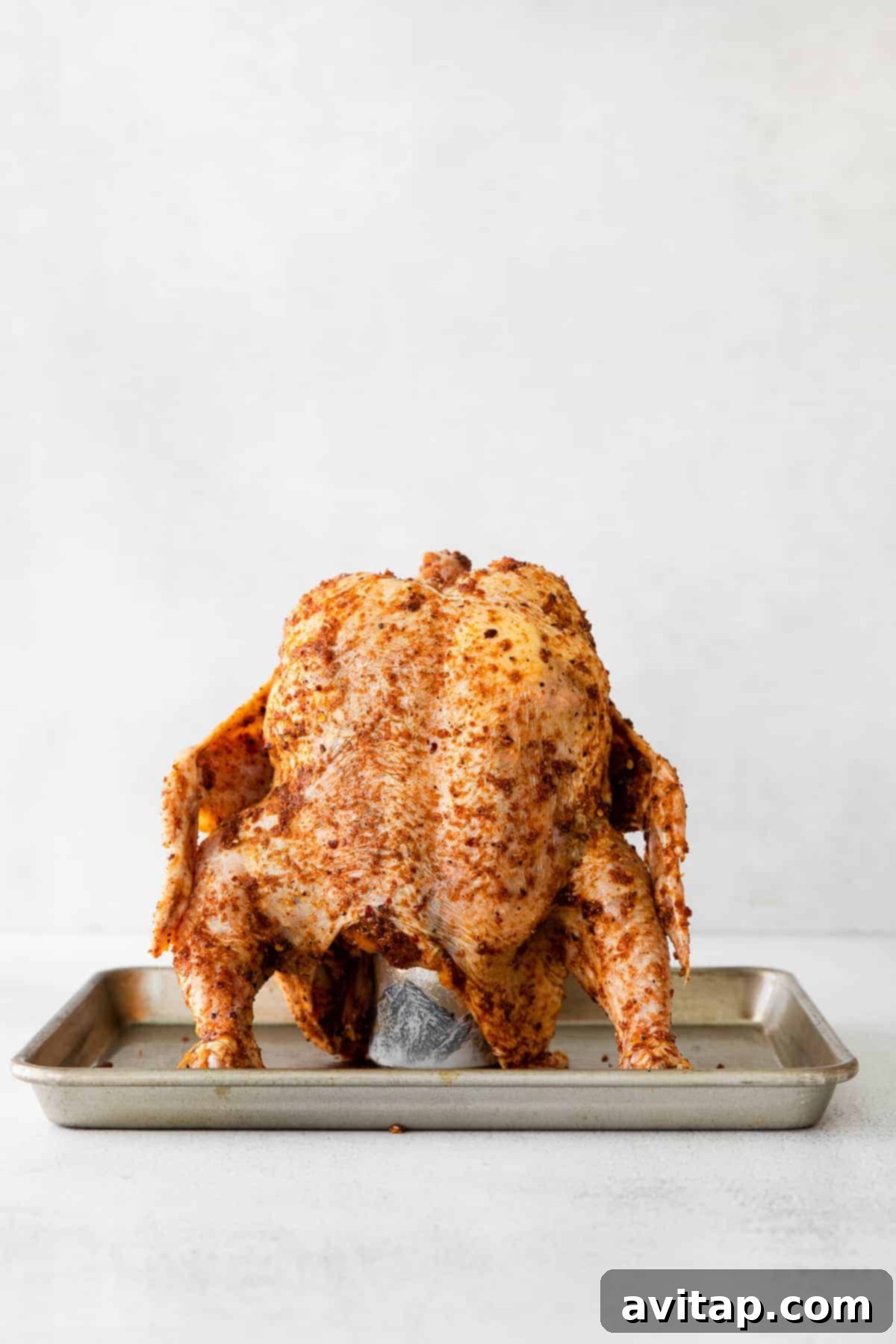 Perfectly Cooked Beer Can Chicken A glistening beer can chicken, fresh out of the oven, resting on a roasting pan, exhibiting its perfect golden-brown color.