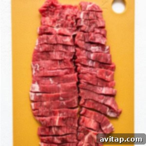 Precisely sliced flank steak, arranged on a wooden cutting board, ready for the next step in the Instant Pot Beef and Broccoli recipe.