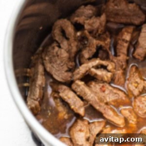Tender, sauced beef after pressure cooking, resting in the Instant Pot, ready for the next step.
