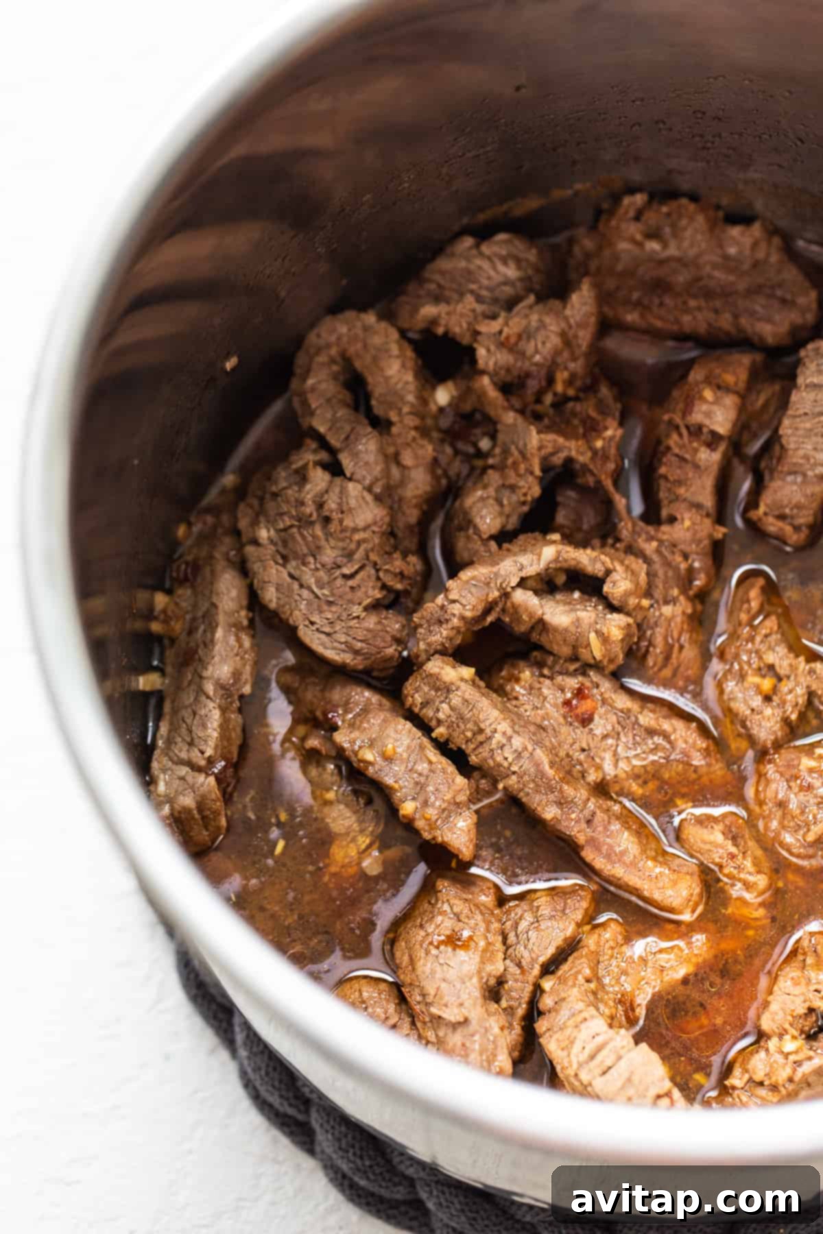 Tender, seared beef cooking in the Instant Pot, infused with aromatics and ready for pressure cooking to achieve ultimate tenderness.
