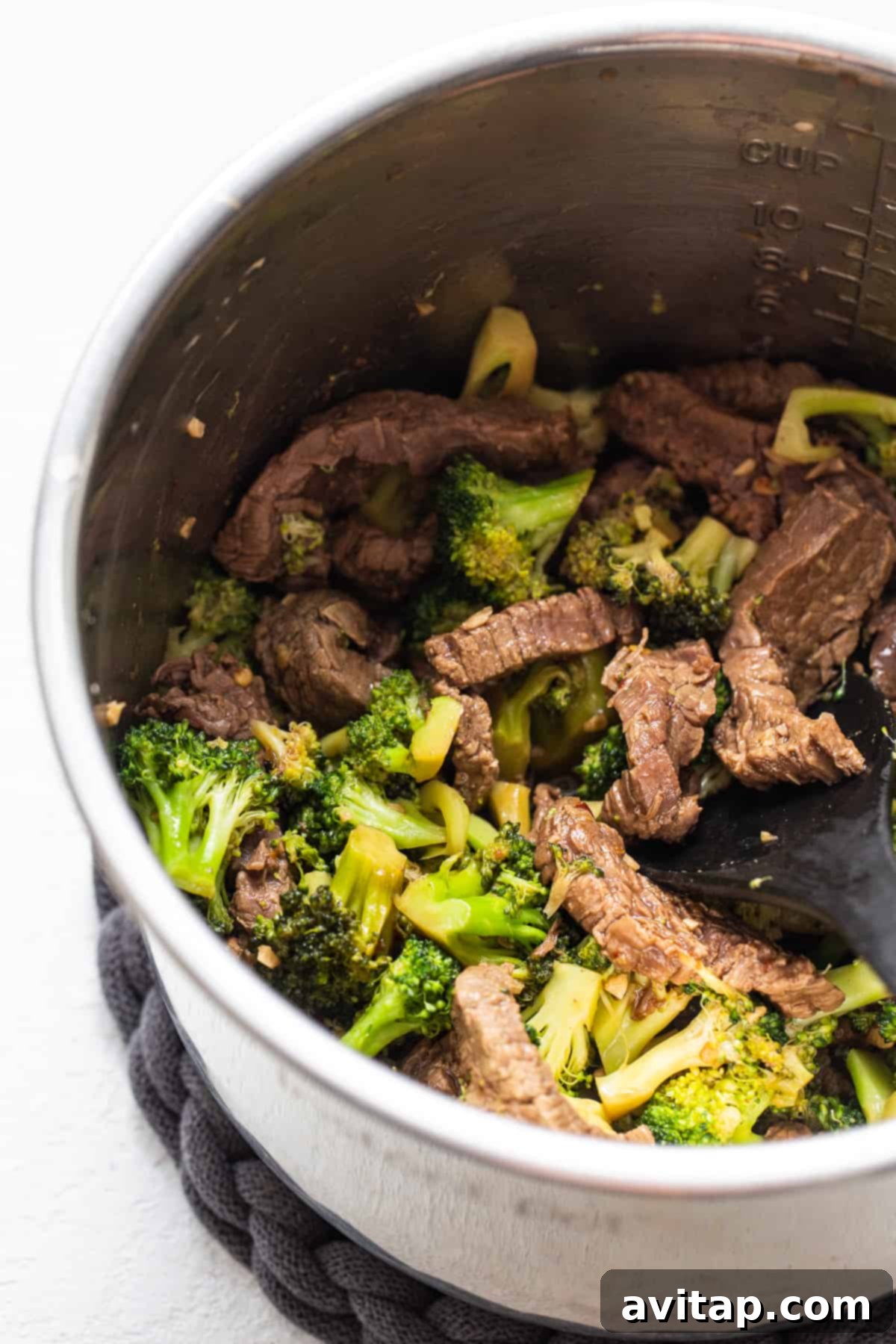 Freshly cooked broccoli mixed with tender beef and savory sauce inside an Instant Pot, ensuring crisp-tender vegetables.