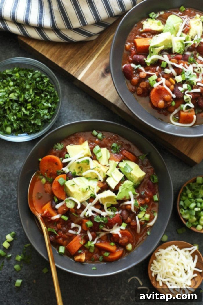 A vibrant bowl of Instant Pot Vegan Chili artfully topped with fresh avocado slices and a generous sprinkle of vegan shredded cheese, showcasing a perfect balance of flavors and textures.