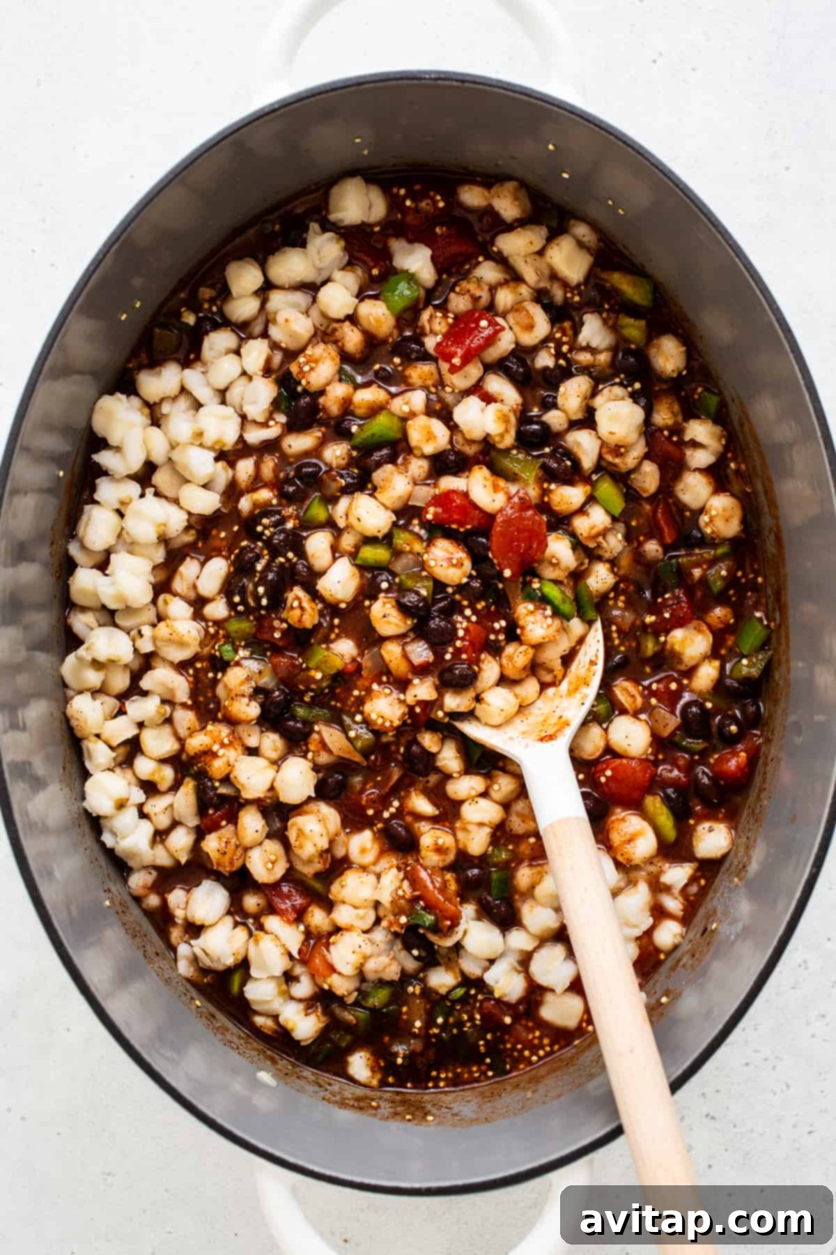 A collection of fresh black bean quinoa chili ingredients, including vibrant vegetables, beans, and spices, neatly arranged in a Dutch oven before cooking.