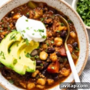A bowl of black bean chili with avocado and sour cream.