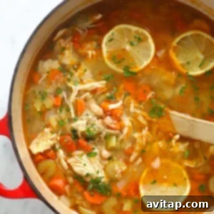 a pot of chicken soup with lemon wedges.