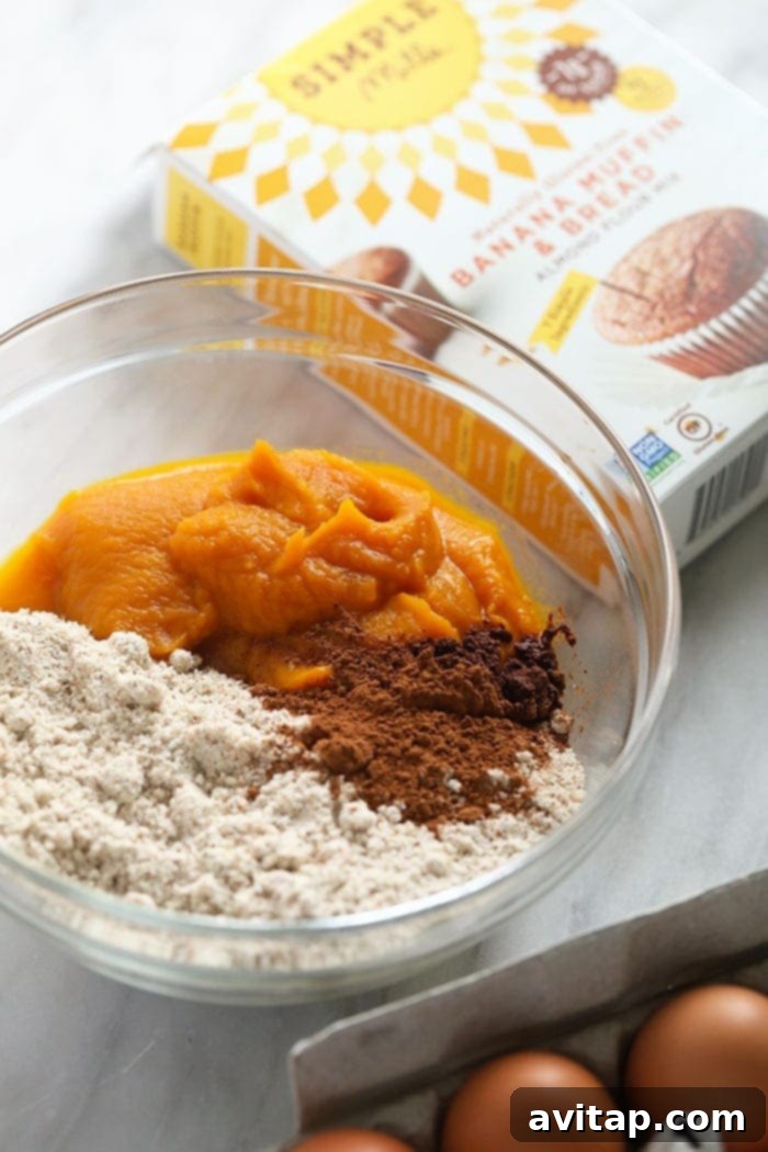 Gluten-Free Pumpkin Muffin Ingredients in a Bowl All the raw ingredients for gluten-free pumpkin muffins, including the mix, pumpkin puree, eggs, and spices, combined in a large mixing bowl.