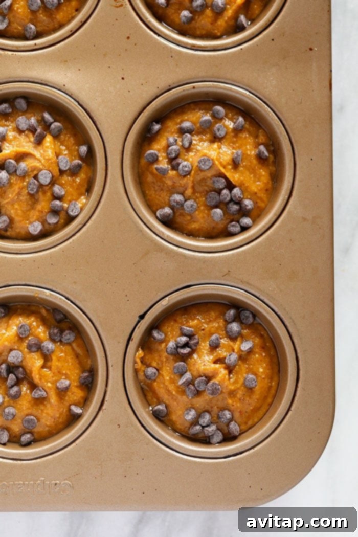 Gluten-Free Pumpkin Muffin Batter in Pan The gluten-free pumpkin muffin batter expertly poured into the cups of a muffin pan, ready for baking.