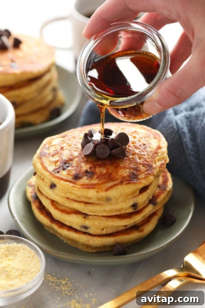 pouring maple syrup onto a stack of gluten-free cornbread pancakes
