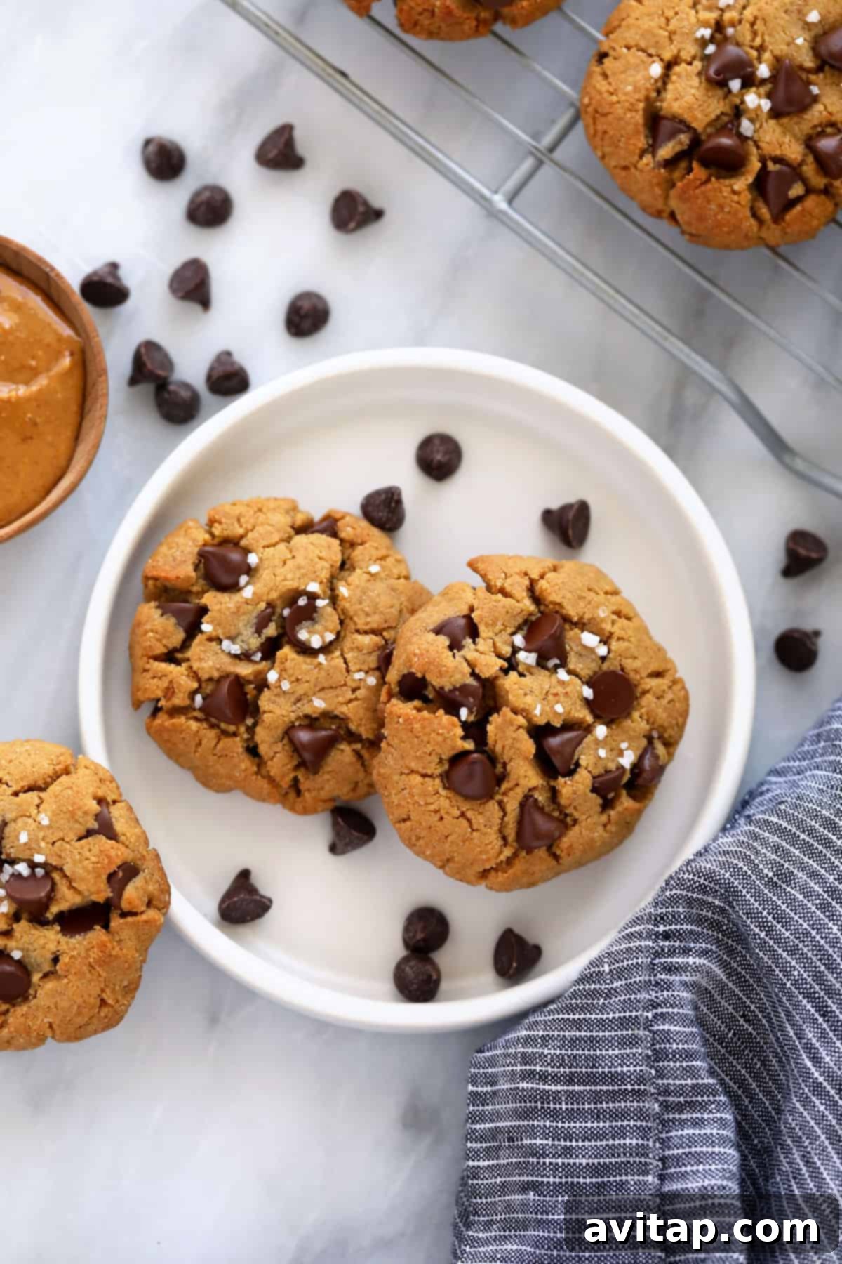 A plate filled with freshly baked healthy peanut butter cookies, adorned with dark chocolate chips and sea salt.