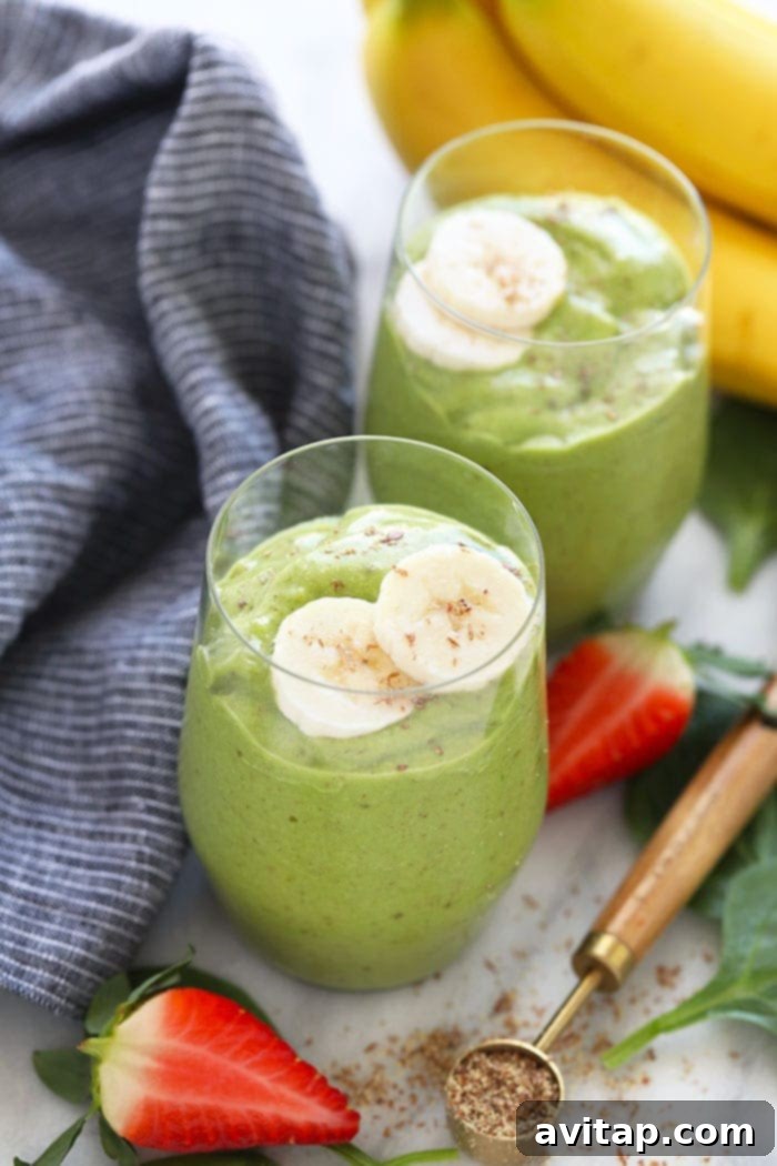 Two glasses of vibrant green smoothie, garnished with banana slices, ready to be enjoyed.