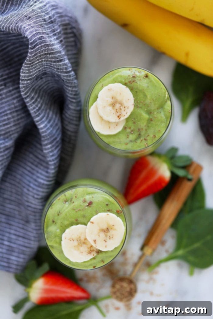 A top-down view of two healthy green smoothies, artfully presented with fruit toppings, emphasizing their refreshing appeal.