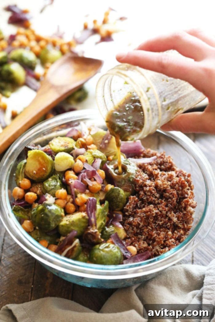 Crispy Roasted Brussels Sprout Quinoa Salad 4 Pouring homemade balsamic vinaigrette into a bowl of roasted vegetables and quinoa, ready to be mixed.