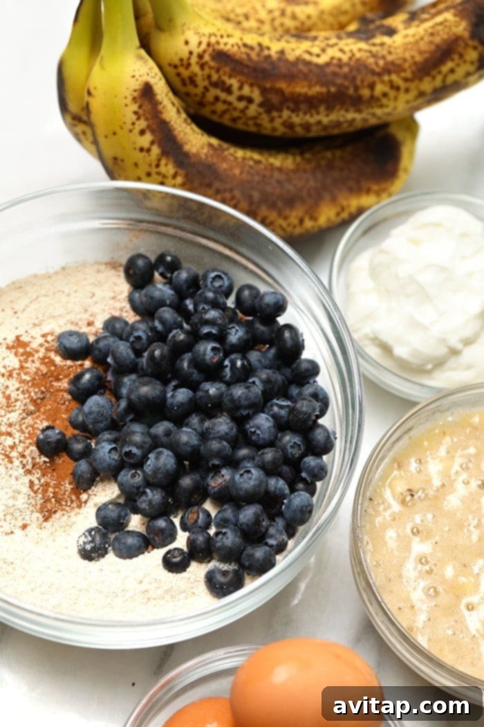 This healthy blueberry banana bread is an easy breakfast that the whole family will love! It is naturally sweetened, delicious and you just can’t beat moist banana bread. Make a loaf today! A bowl of ingredients, including flour, bananas, and blueberries, ready to be mixed for banana bread.