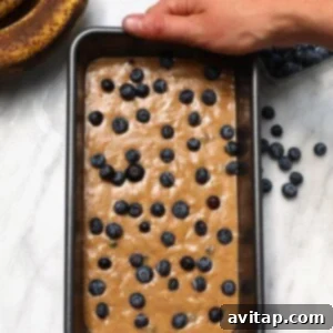 Blueberry Banana Burst Loaf 4 A person holding a pan of blueberry banana bread before baking.