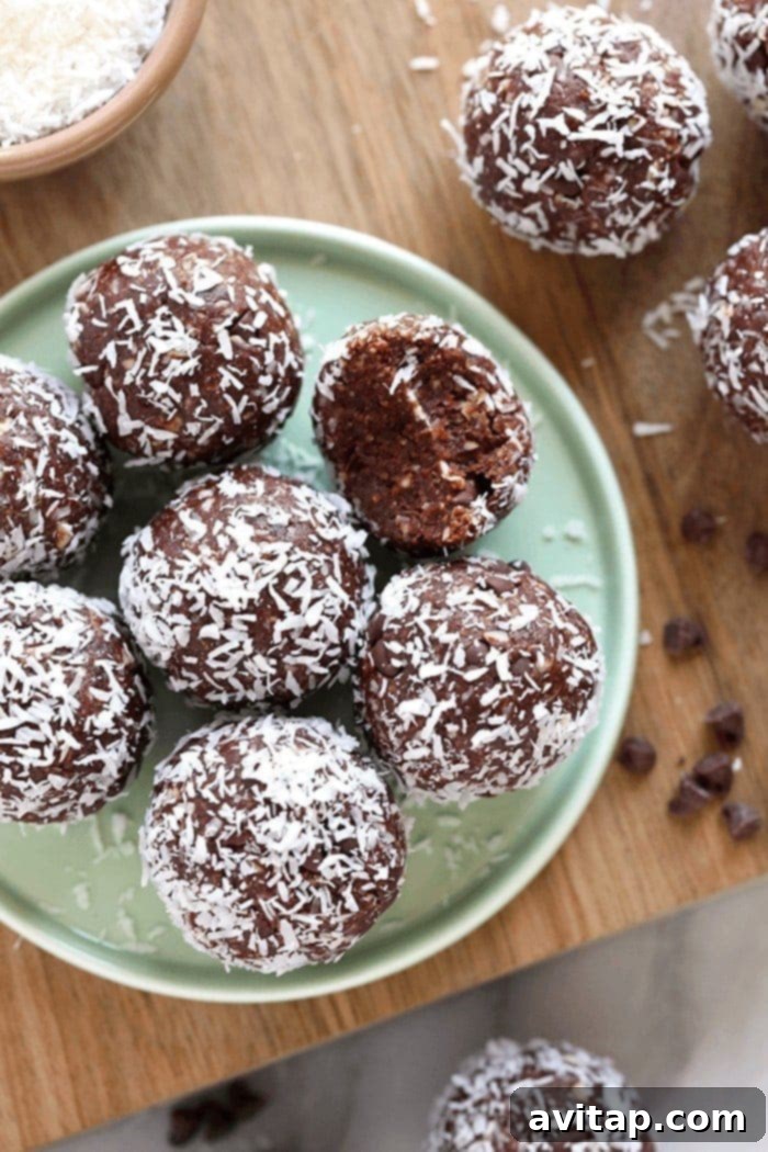 Easy coconut chocolate energy balls for healthy meal prep and delicious snacking. A close-up shot of delicious coconut chocolate energy balls, with some rolled in shredded coconut flakes, highlighting their texture and tempting appeal.