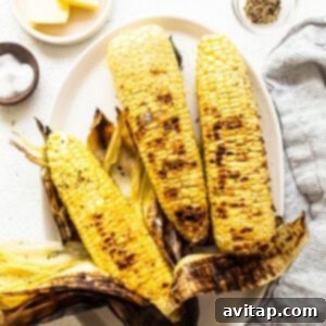 Golden Summer Corn Salad 3 Three ears of perfectly grilled corn on a plate, seasoned and ready to eat.