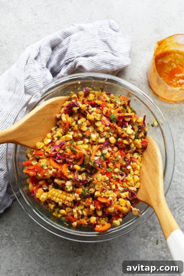 Serve this delightful Thai Chili Corn Salad as a versatile side dish with your favorite burgers, chicken, or other easy weeknight dinners. It's sure to become a new family favorite! A large bowl of Thai Chili Corn Salad ready to be served, accompanied by cutlery.