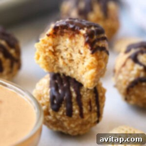 Crunchy no bake peanut butter balls stacked pyramid style on a white surface.