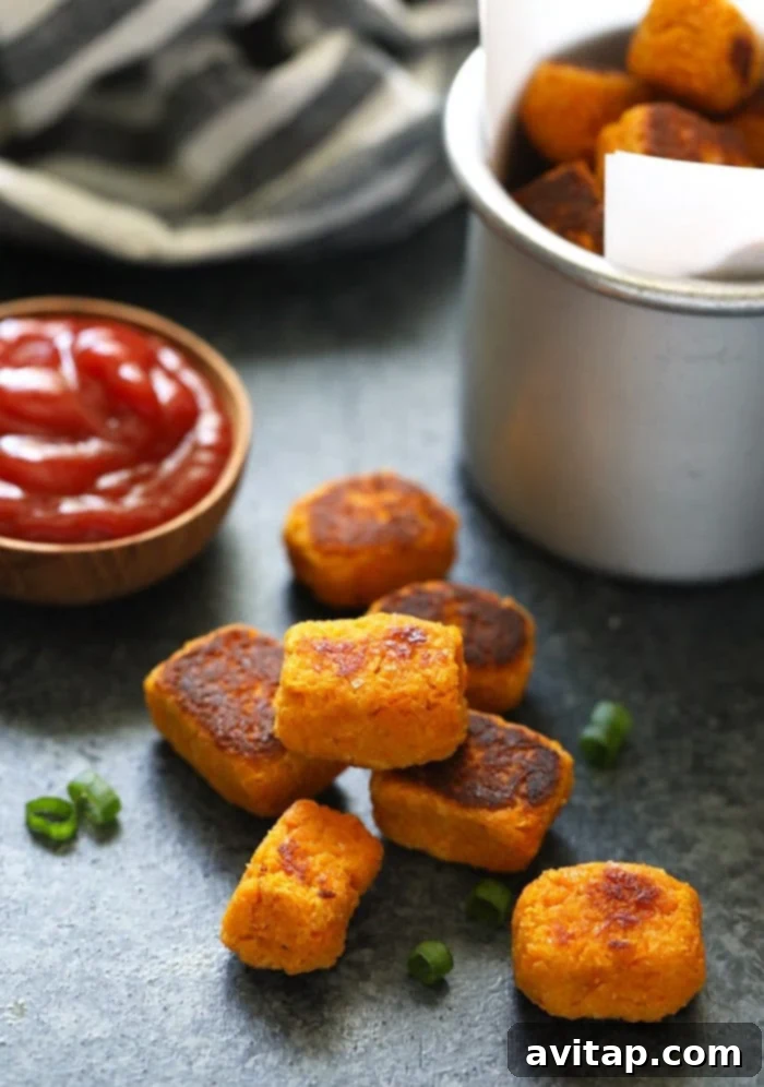 A perfectly stacked pyramid of golden sweet potato tater tots, showcasing their tempting texture.