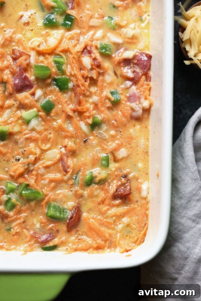A large baking dish filled with the uncooked Sweet Potato Hash Breakfast Casserole, showcasing the vibrant mix of ingredients.
