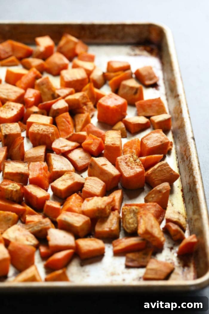 Prepare your sweet potatoes for roasting to achieve perfect tenderness and caramelization, building the foundation of your casserole. Diced sweet potatoes seasoned with olive oil and ready to be placed on a baking sheet for roasting.