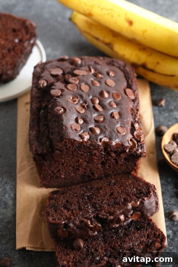 Freshly baked banana bread on a cutting board with bananas