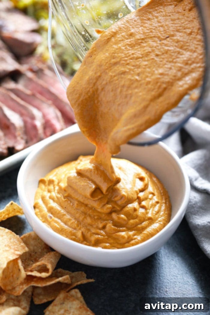 Thick, creamy vegan queso being poured into a serving bowl.