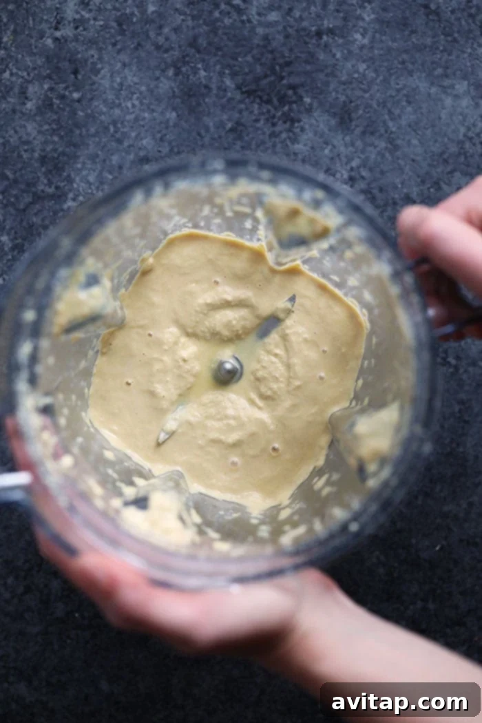 A high-speed blender containing a silky smooth cashew cream sauce, ready to be transformed into vegan mac and cheese.