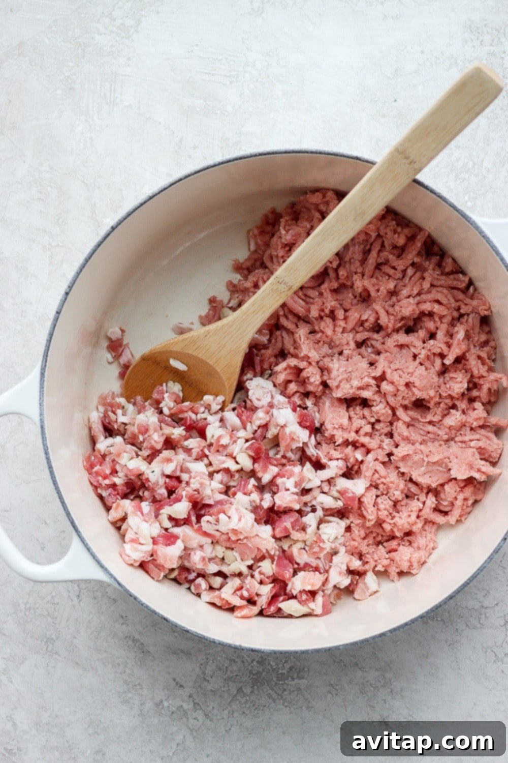 Fresh ingredients for turkey farro soup including kale, mushrooms, ground turkey, and farro, neatly arranged in a large cooking pot before simmering.