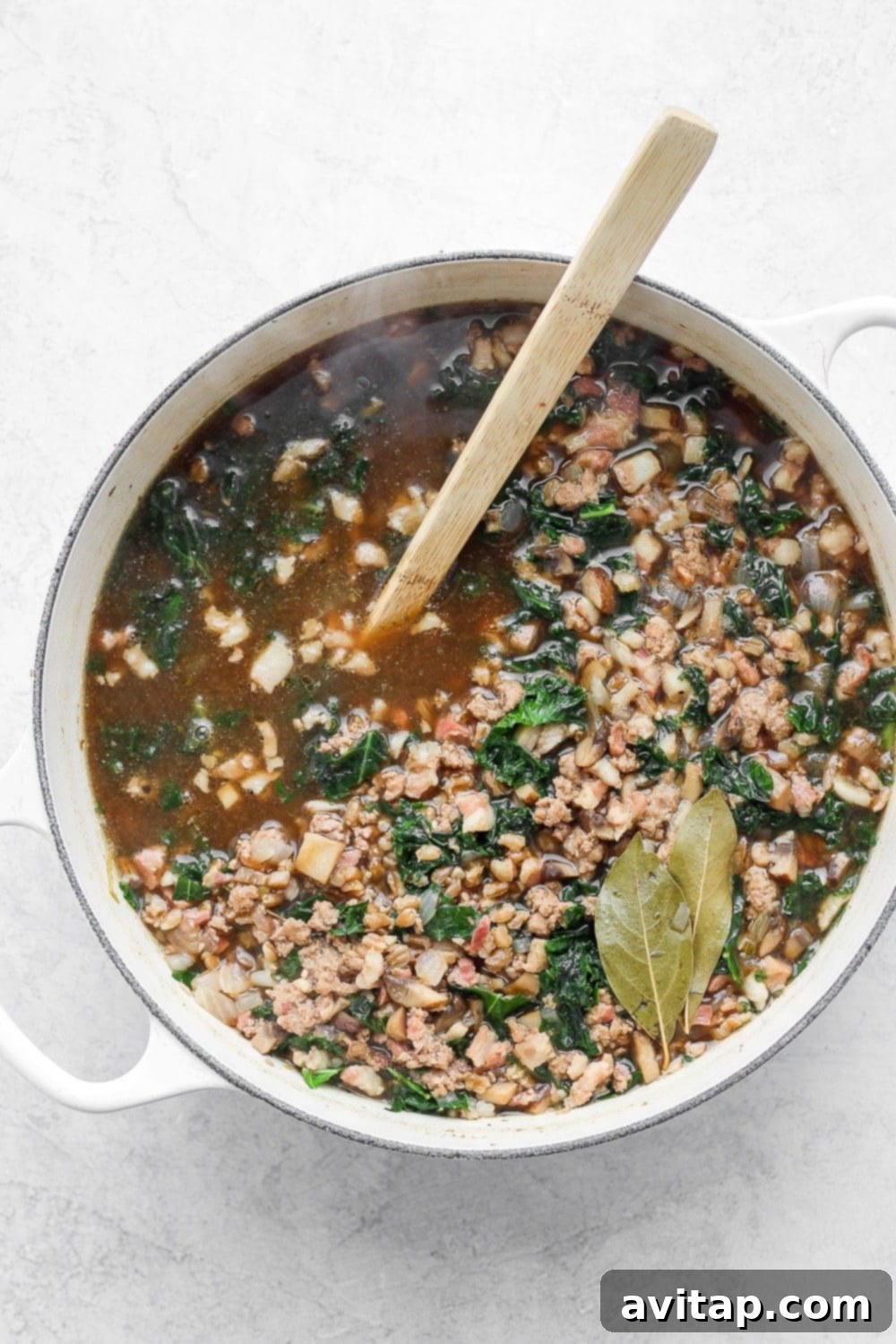 A large pot of freshly cooked turkey farro soup with kale, ready to be served, showing its rich texture and vibrant colors.