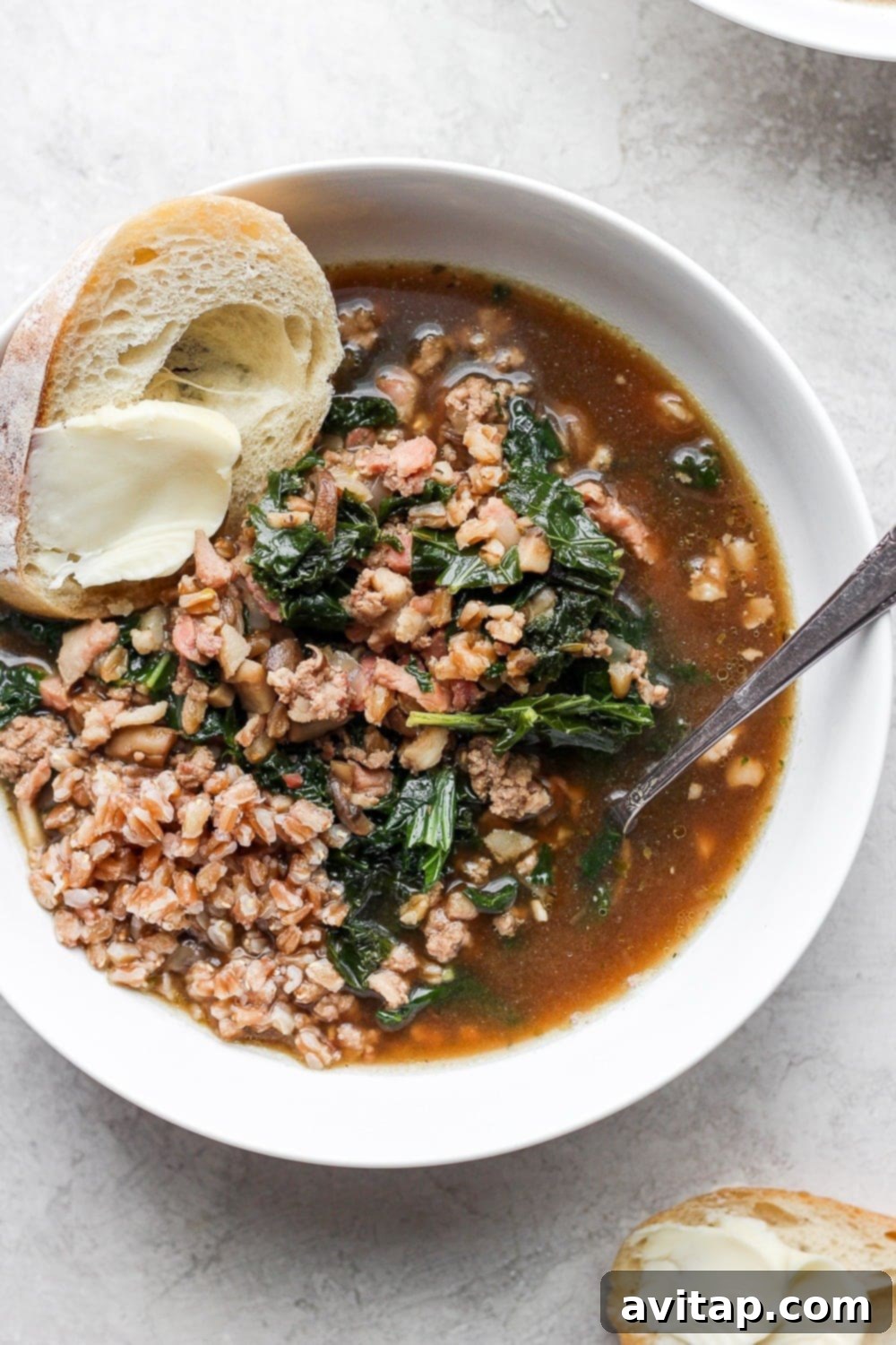 A close-up of a bowl of delicious turkey farro soup with kale, garnished with fresh herbs, ready to be enjoyed.