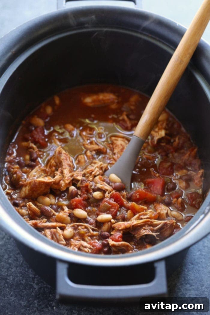 Shredded chicken chili stirred into the slow cooker, ready for serving.