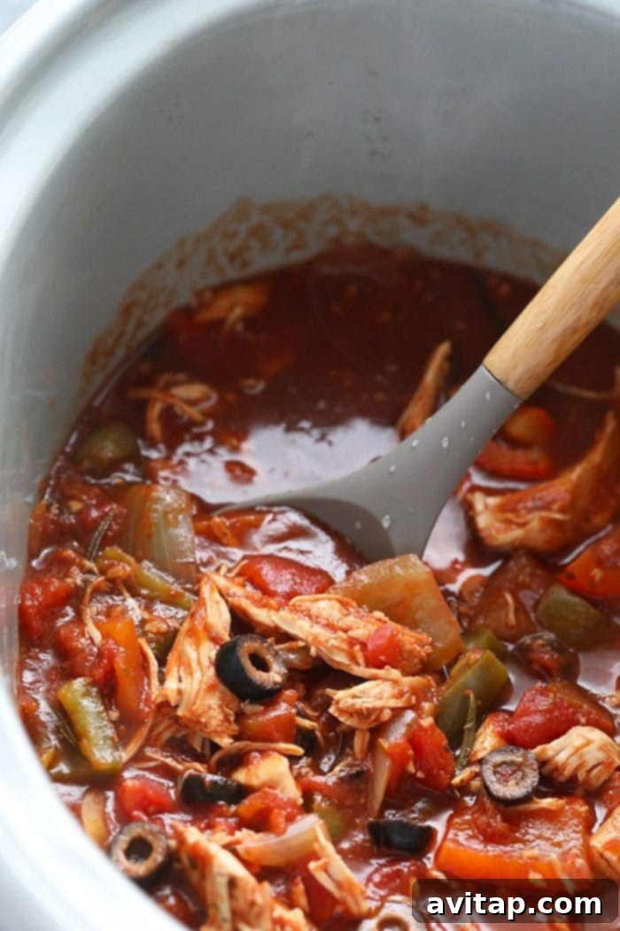 Hearty slow cooker chicken cacciatore served with fresh pappardelle pasta, garnished with Parmesan cheese and herbs.