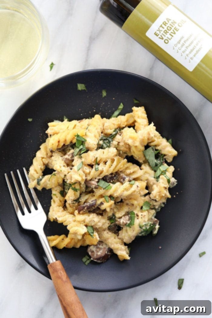 Creamy vegan pasta bake with white wine sauce on a plate, garnished with fresh herbs.