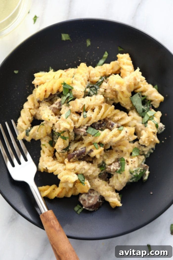A bowl of creamy vegan pasta bake with white wine cashew sauce, garnished with fresh basil.