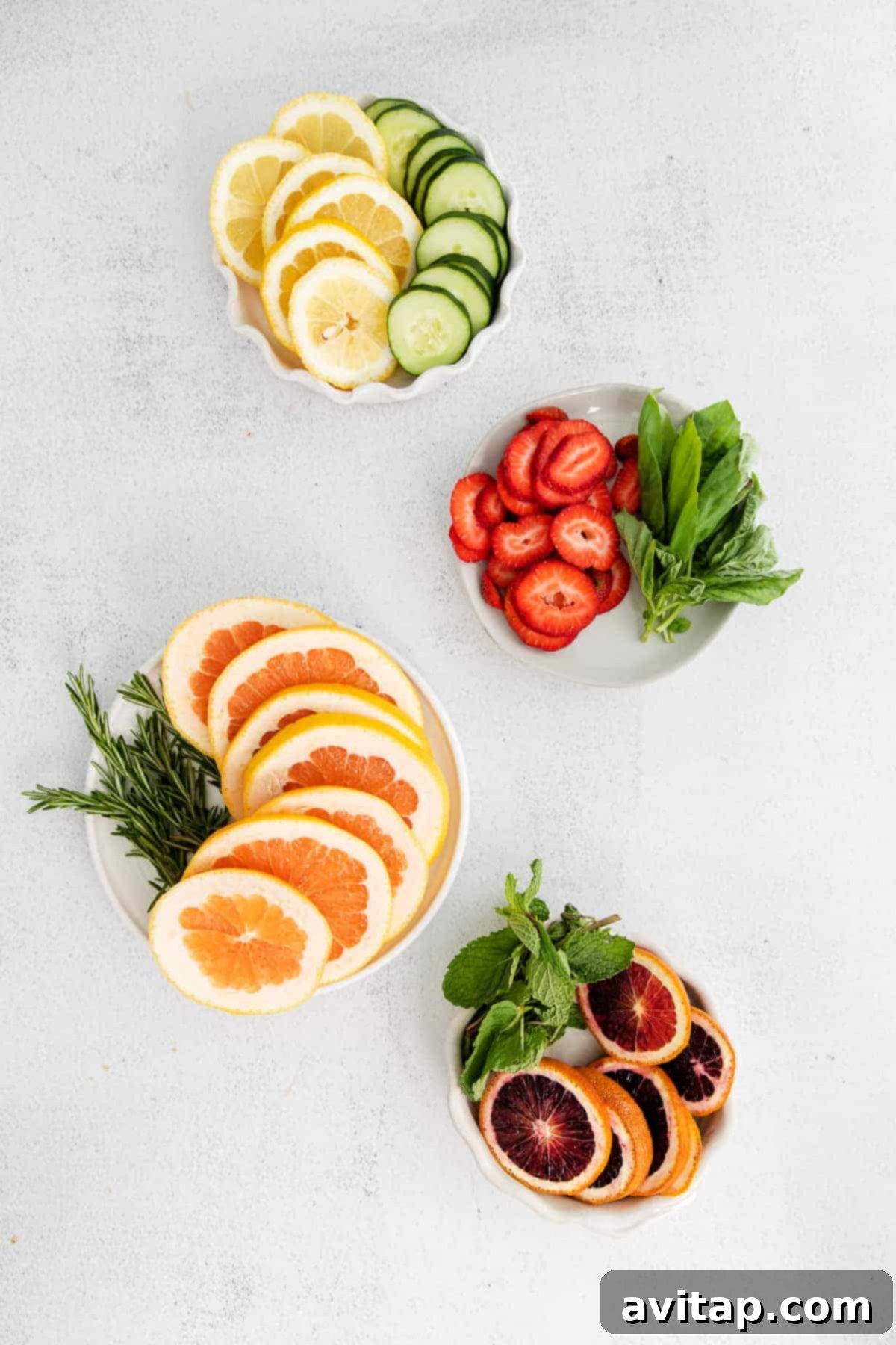 Assortment of fresh fruits and herbs laid out for fruit infused water preparations, including berries, citrus, mint, and rosemary.