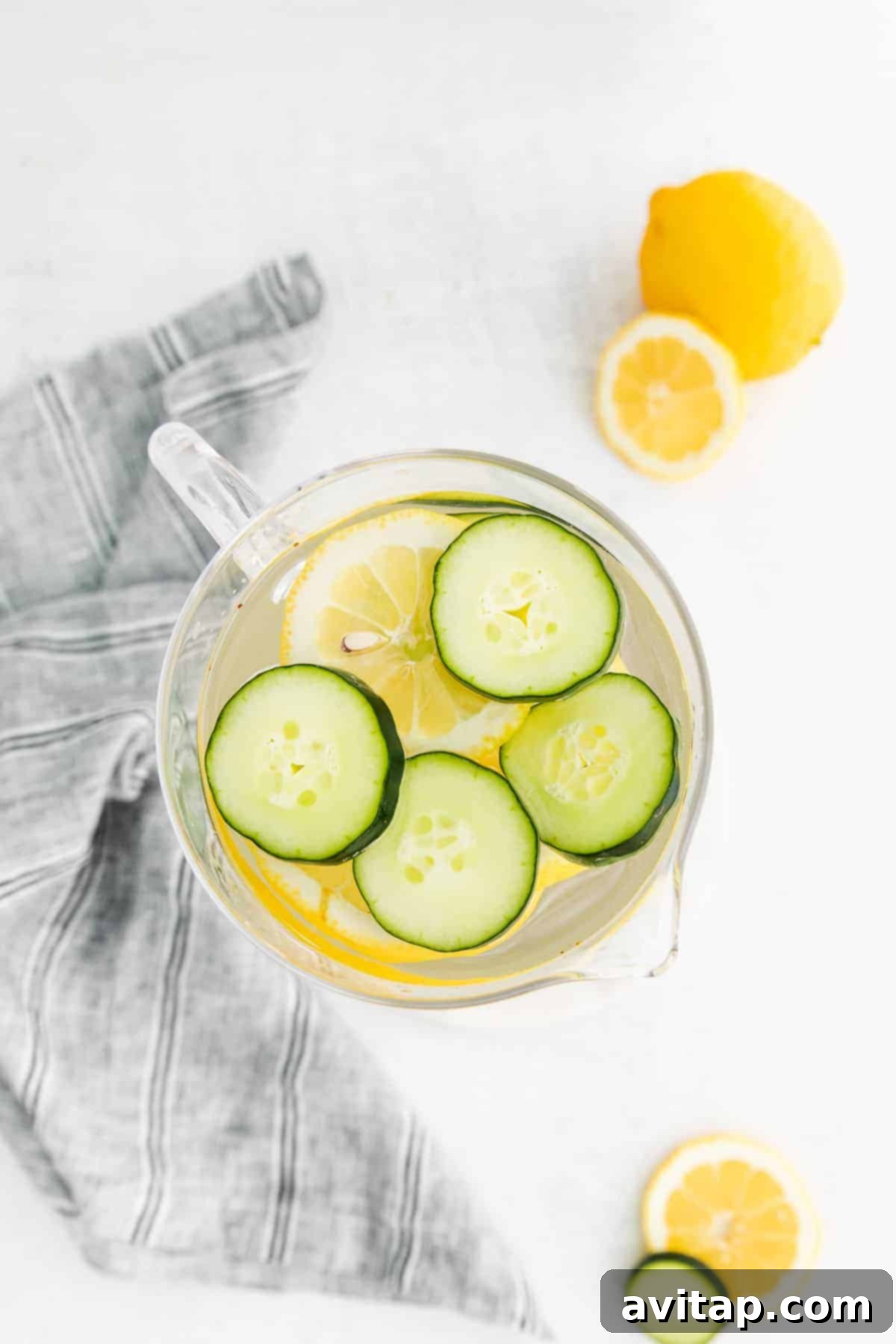 Refreshing lemon and cucumber fruit infused water in a glass pitcher with ice.
