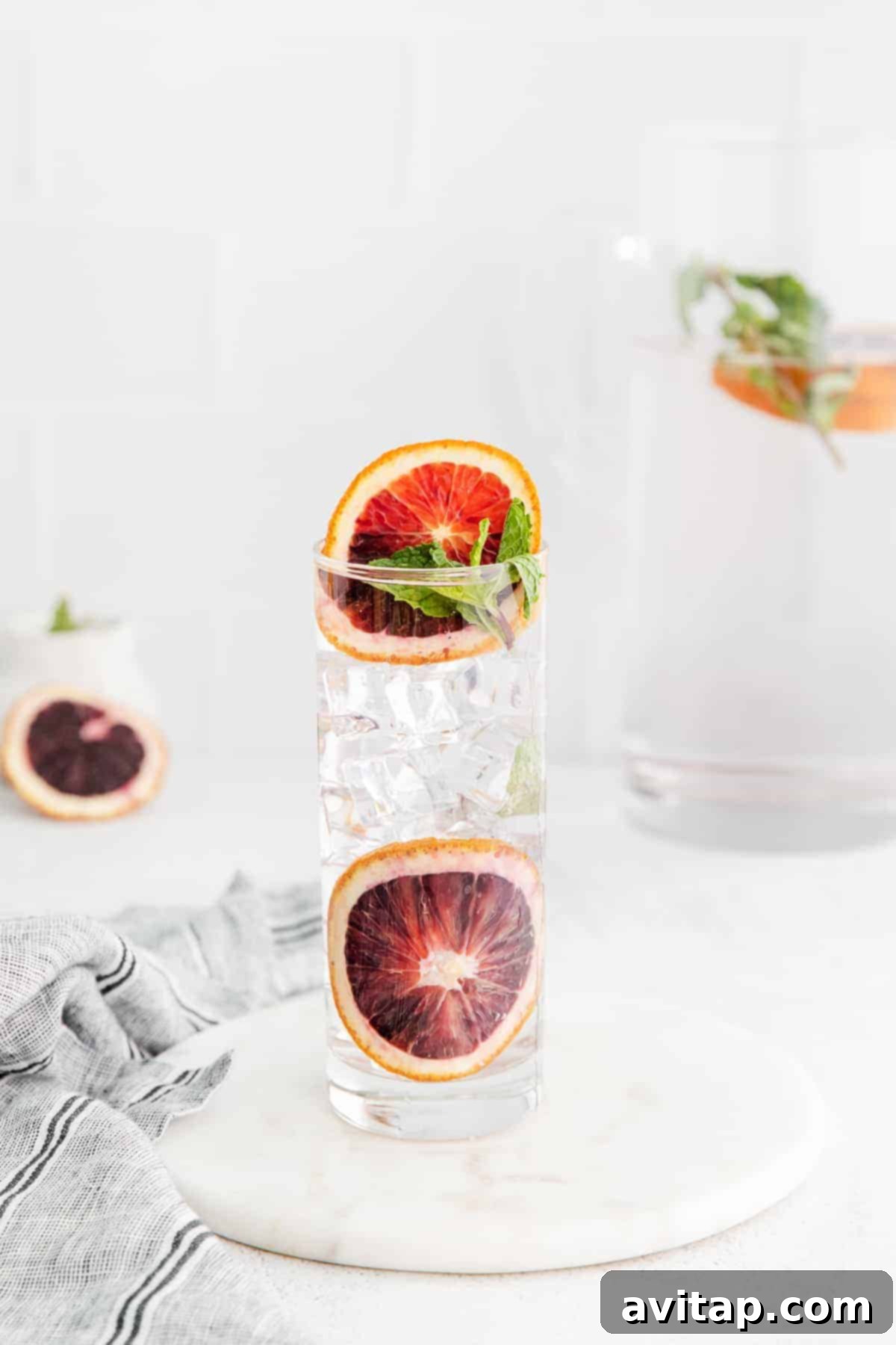 Close-up of blood orange slices and fresh mint leaves infusing in a glass of water.