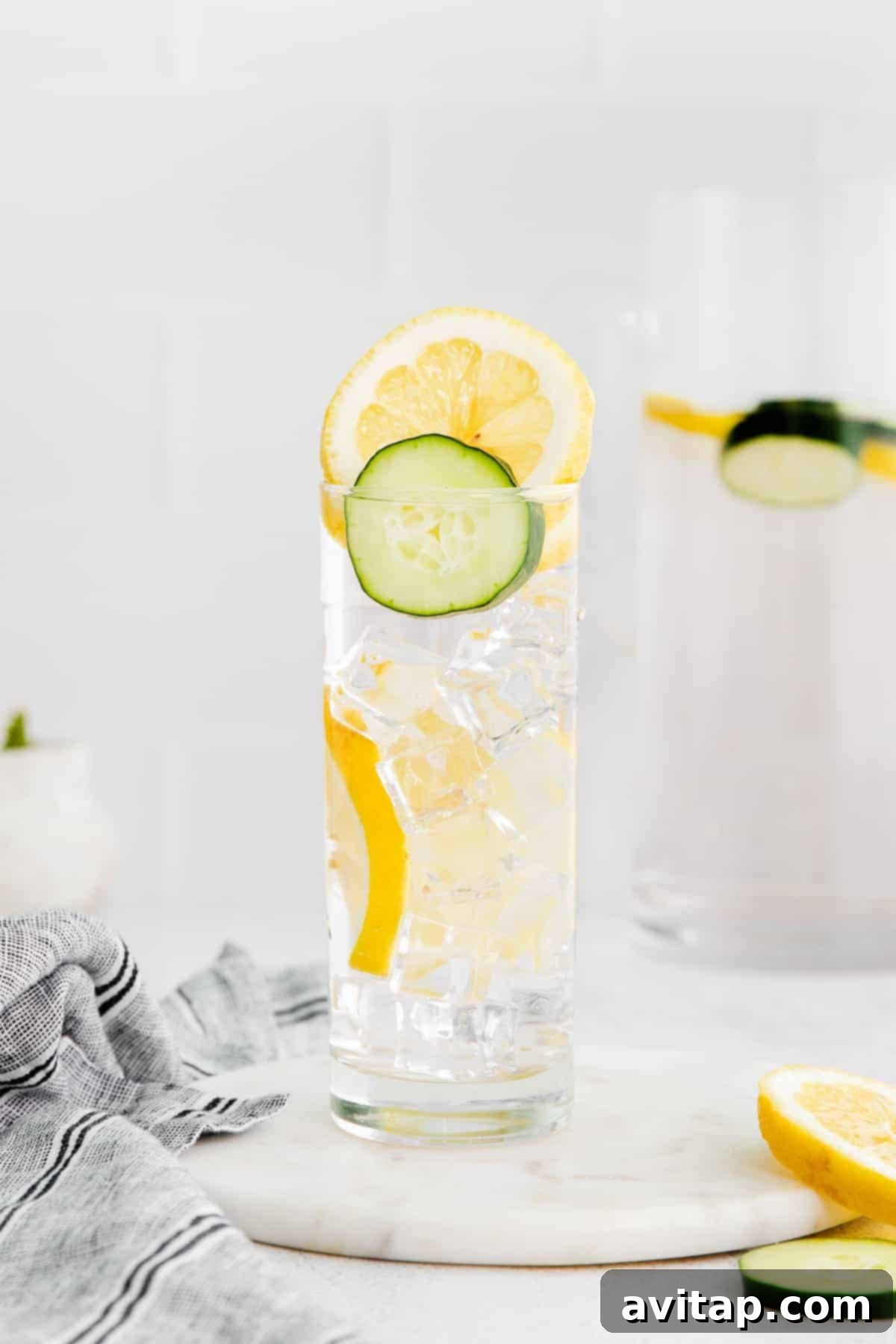 Slices of cucumber and lemon infusing in a clear glass of water.
