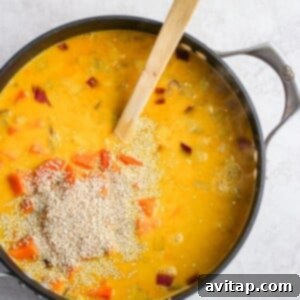 A steaming bowl of curry chicken soup with a wooden spoon in it.