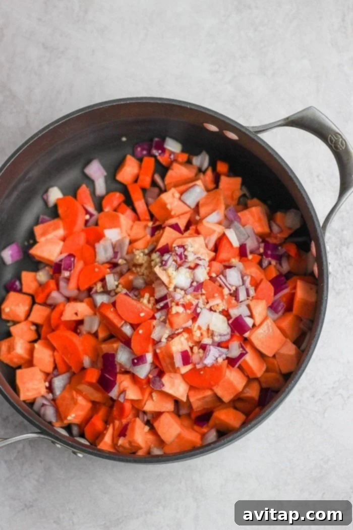 Close up of cooked carrots and onions in a pan for curry chicken soup.
