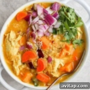 A bowl of chicken curry soup with carrots and onions.