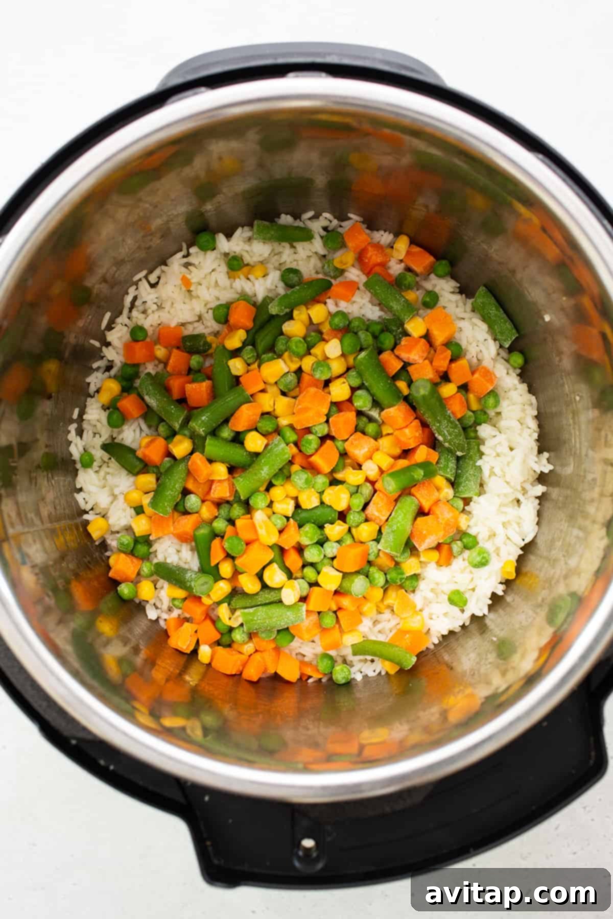Cooked rice and frozen vegetables being sautéed in an Instant Pot.