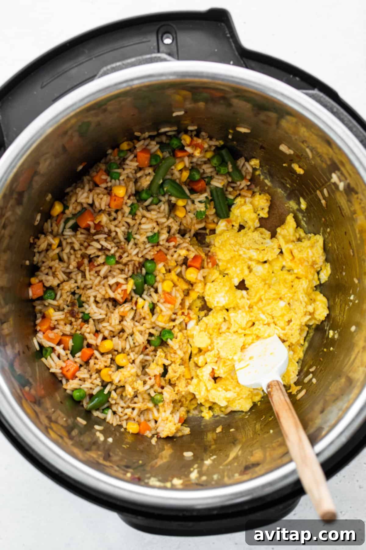 Scrambled eggs being folded into the fried rice mixture within the Instant Pot.