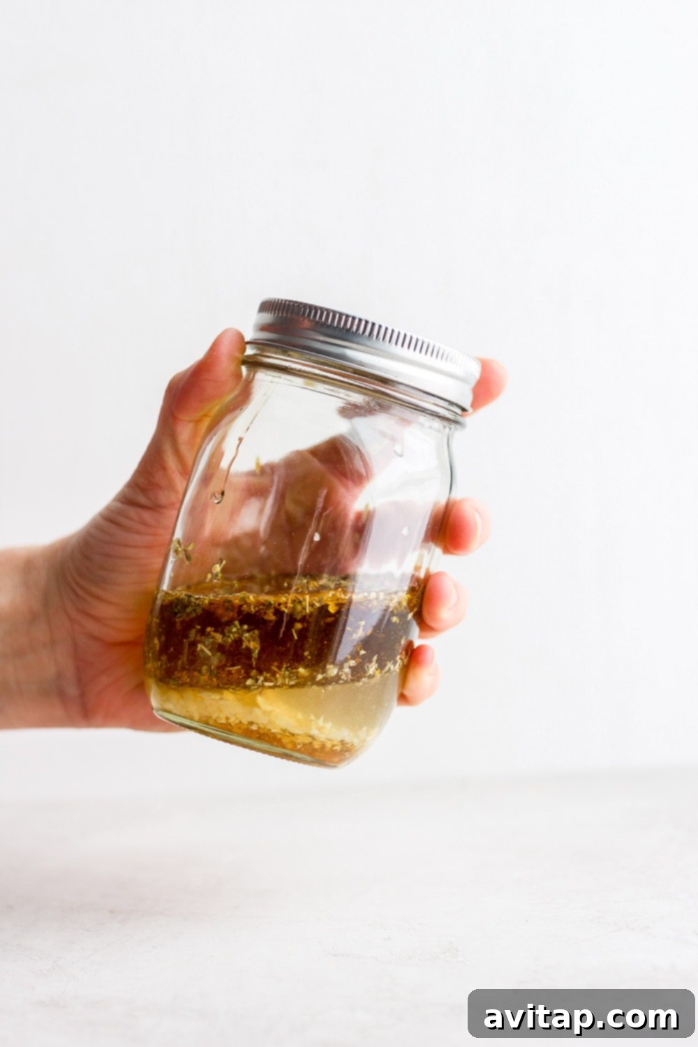 A bottle of fresh Greek salad dressing, showcasing its vibrant color and appealing texture.