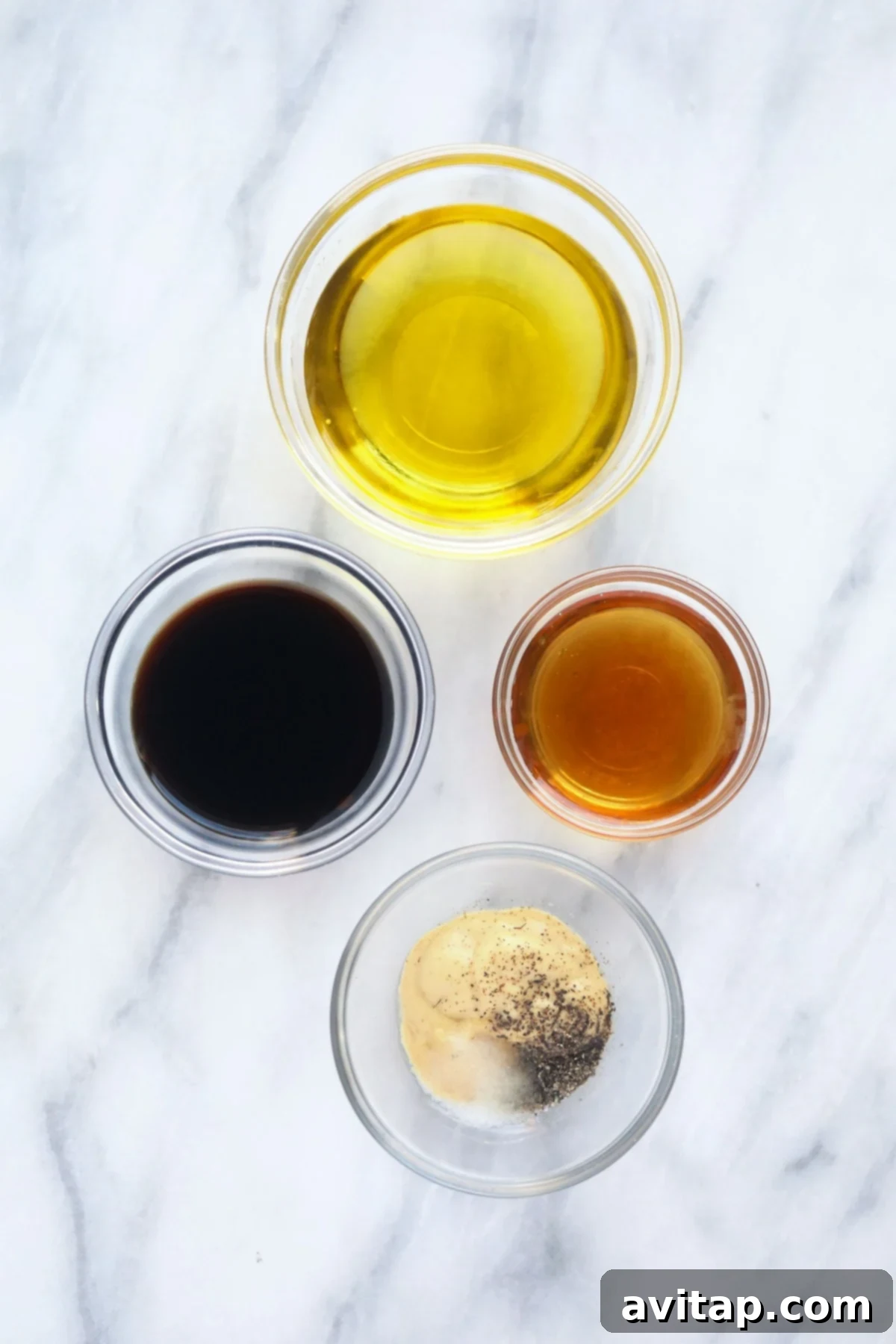 Various essential ingredients for making homemade salad dressing, including fresh herbs, oil, vinegar, and citrus, arranged on a rustic wooden board.