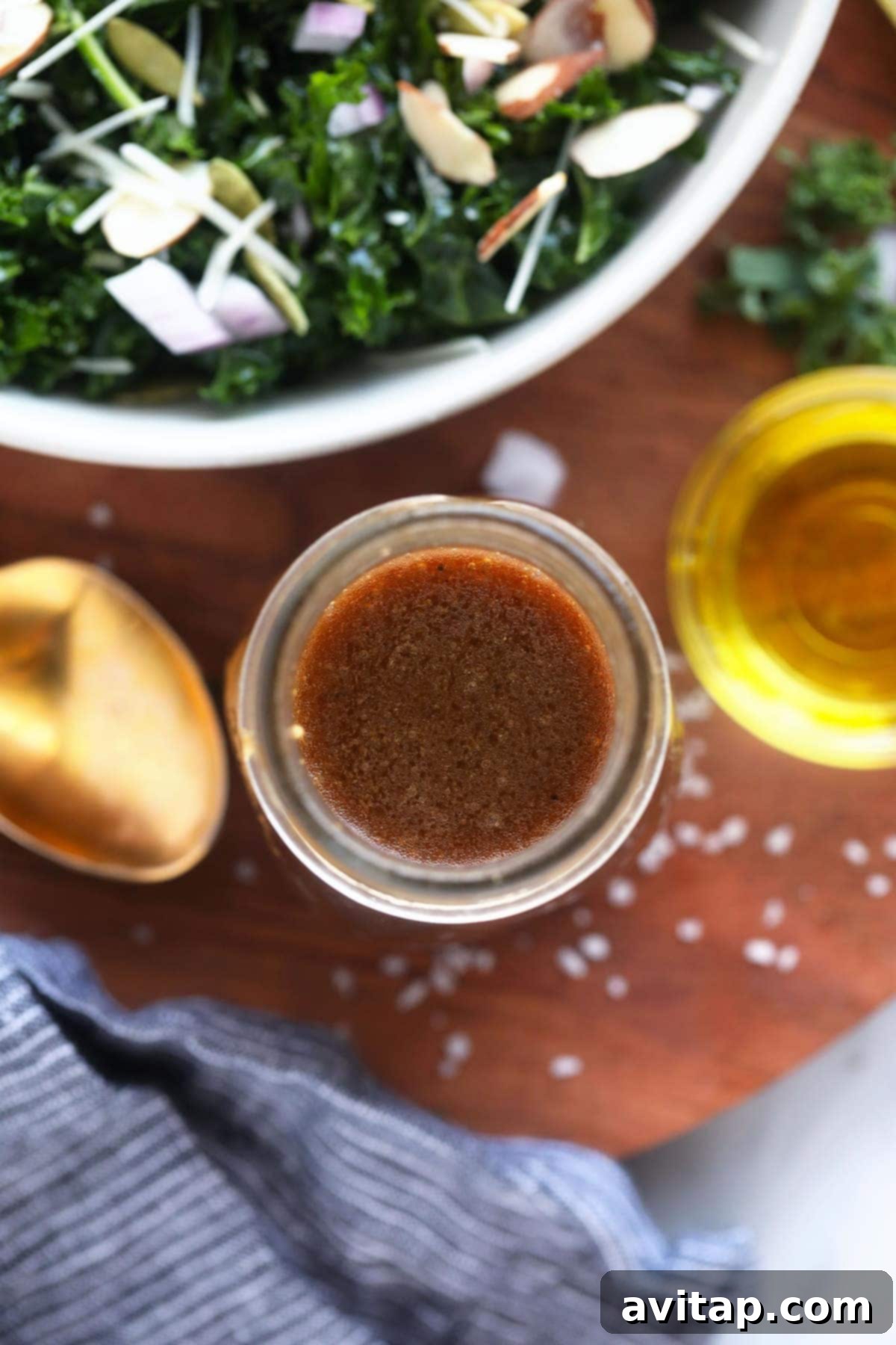 A bottle of homemade balsamic vinaigrette next to a spoon, ready to be drizzled over a fresh salad.
