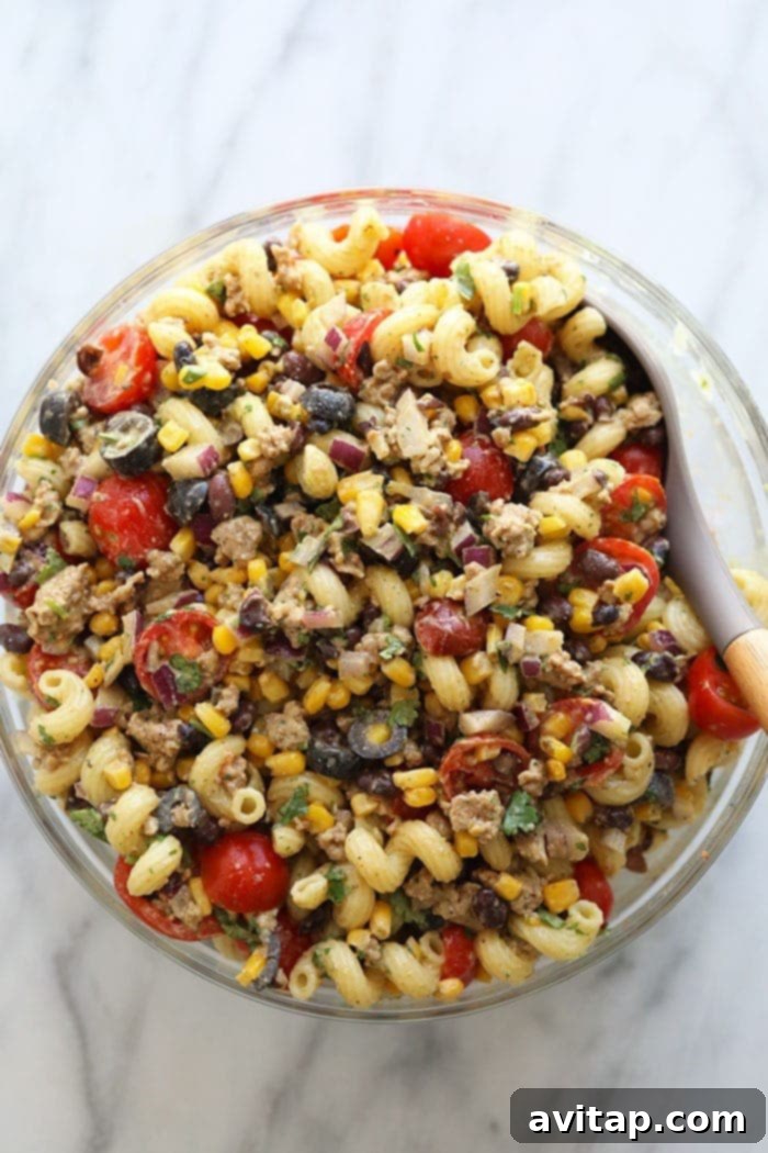 Healthy Taco Pasta Salad in a large glass serving bowl, beautifully garnished with fresh cilantro and a lime wedge, ready to be enjoyed.
