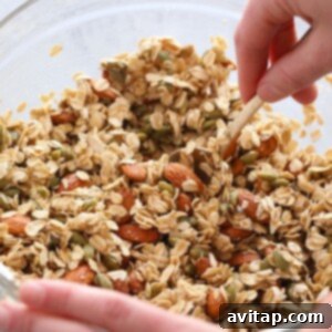 Effortless Granola Bliss 3 A person preparing a healthy granola recipe, mixing ingredients in a glass bowl.