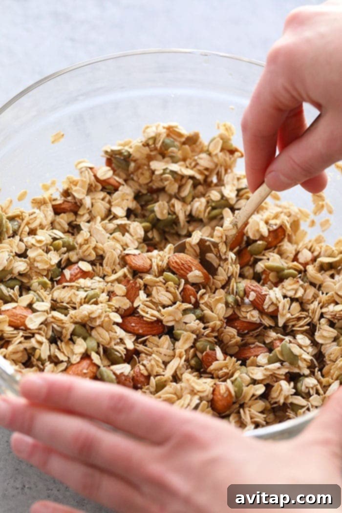 Mixing Homemade Granola Ingredients Hands mixing healthy granola ingredients in a large bowl before baking.